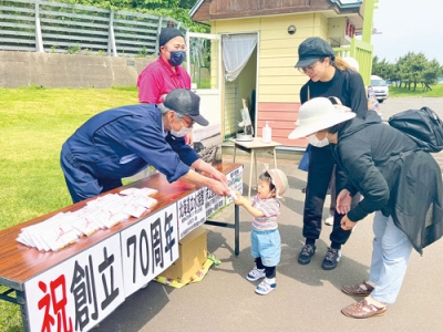 写真：開館７０周年を記念したクッキーを手渡す中沢館長（左）