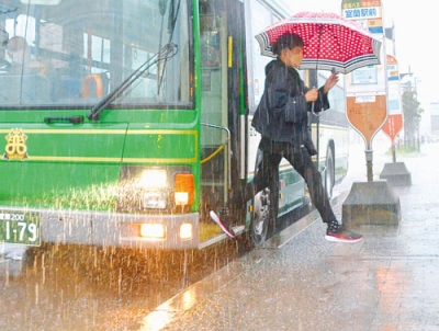 写真：水たまりをよけてバスを降りる乗客＝午前１１時ごろ、室蘭市中央町