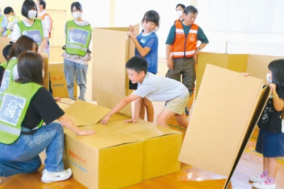 写真：段ボールベッド作りに取り組む児童ら
