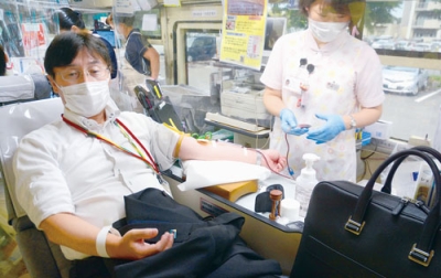 写真：献血に協力する小林会長