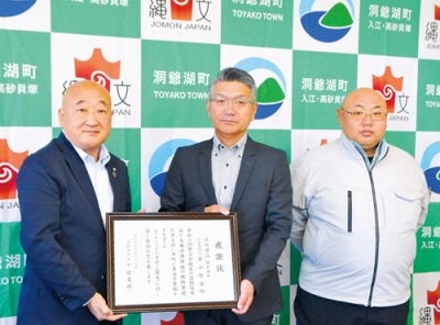 写真：感謝状を手にする河島専務取締役（中央）