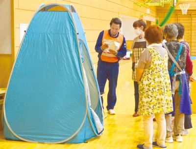 写真：非常食や簡易トイレの説明を受ける参加者