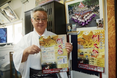 写真：ポスターを手に例大祭を周知する鈴木宮司