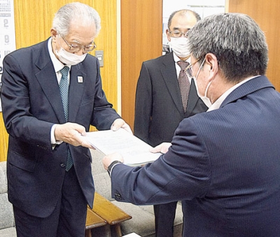 写真：「ぷやら」を市教委に寄贈する日野会長（左）