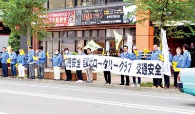 写真：横断幕や旗を手に安全運転を訴える会員