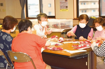 写真：赤い羽根のしおりを作成する奉仕員ら
