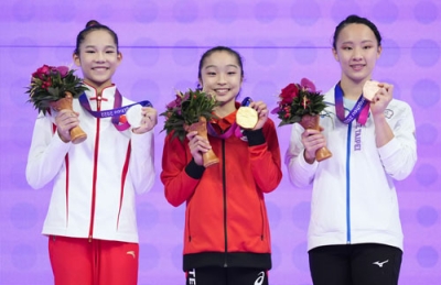 写真：体操女子種目別平均台で優勝し、金メダルを掲げる岡村真（中央）＝杭州（共同）