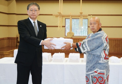 写真：返還された遺骨を受け取る藤原会長（右）