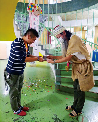 写真：らせん階段の前で記念品を受け取る小林さん（左）