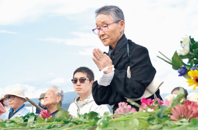 写真：慰霊の集いで花を手向け手を合わせる参加者