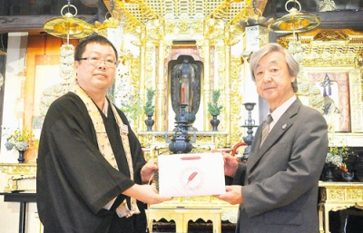 写真：長谷川会長（右）に募金箱を手渡す髙倉住職