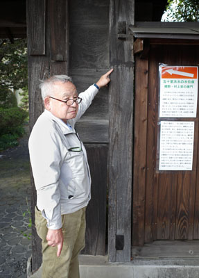 写真：五十里洪水の痕跡とされる「村上家棟門」の染みを指さす村上泉さん＝１０月、栃木県さくら市