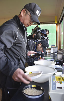 写真：出荷式で「資源米」を検査する担当者＝１０月、東川町