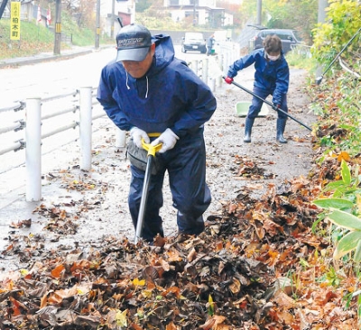 写真：落ち葉をスコップで集める町会員ら
