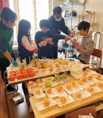 写真：協力しながら菓子作りをするダイナムの従業員と子どもたち