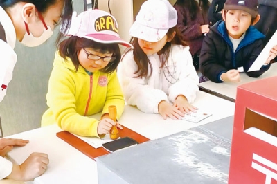 写真：職業体験で消印押しをする園児（提供写真）