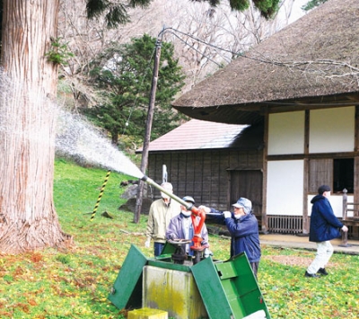 写真：放水銃を扱う参加者たち＝有珠善光寺