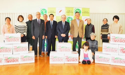 写真：リンゴを寄贈した岩井教区長（中央）らと記念写真に収まる出席者