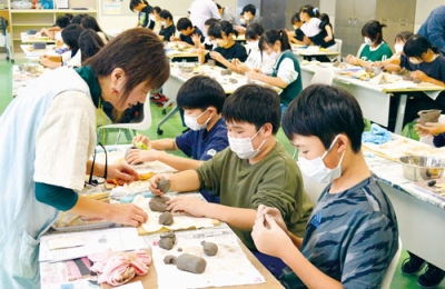 写真：陶芸家木村さん（左）の指導で制作に励む子どもたち