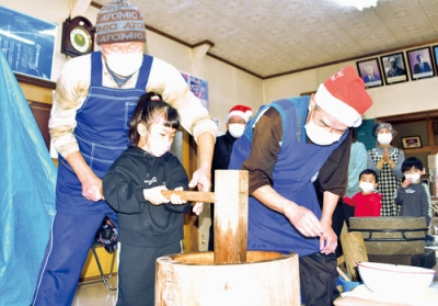 写真：町会役員の助けを借りながら一生懸命餅をつく子ども