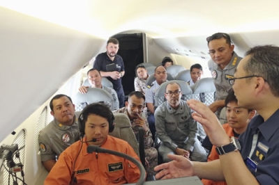 写真：５日、インドネシア・スマトラ島東方海域上空の航空機内で、情報収集の手法について説明を受ける東南アジア諸国の沿岸警備当局者ら（海上保安庁提供、共同）