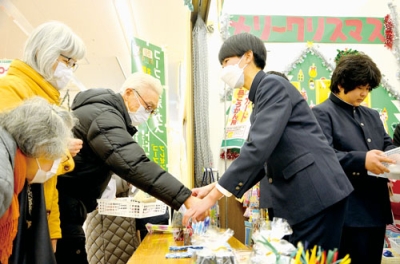 写真：買い物客とコミュニケーションをとる生徒