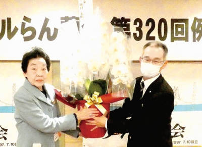 写真：お祝いの花を受け取る三原幹事長（左）