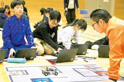 写真：プログラミングした車型ロボットが動くか試した児童ら