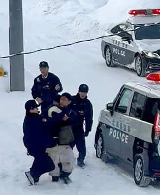 写真：札幌市のコンビニ「セイコーマート北３１条店」近くで複数の警察官に取り押さえられる容疑者（手前中央）＝２５日午前（近隣住民提供）