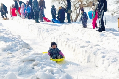 写真：雪の滑り台でソリ滑りする子ども（提供写真）