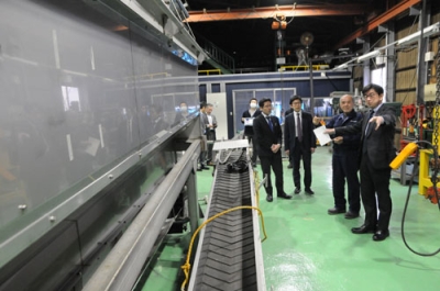 写真：工場内でホタテ水揚げ時に使う機械の説明を受ける大久保局長（右端）