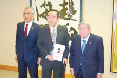 写真：岩倉地区長（中央）に目録を手渡した宮﨑会長（右）と鈴木社長