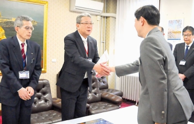 写真：辞令書を受け取り、青山市長と握手を交わす赤木消防長（中央）と塩越事務局長（左）