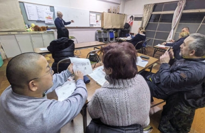 写真：小野一馬さん（手前左）が大分県別府市の集会場で開いているウクライナ避難民の日本語教室。奥は通訳者の山口英文さん＝２月