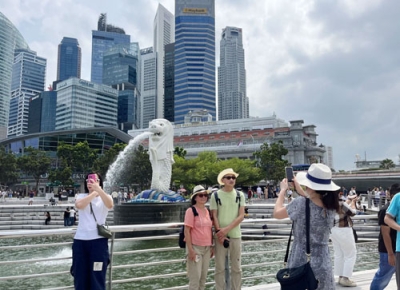 写真：シンガポールのマーライオン像の前で写真撮影する中国人観光客ら＝３月（共同）