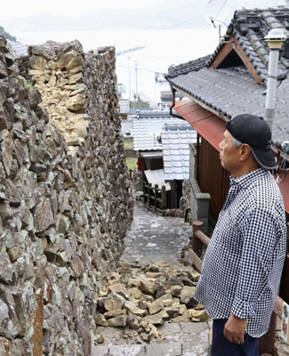 写真：地震の影響で崩れた「石垣の里」の石垣を見つめる住人の吉田誠幸さん＝１８日午前９時４５分、愛媛県愛南町