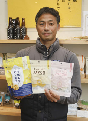 写真：自社製品のポン菓子を手にする沢田米穀店の沢田導俊さん＝４月、北斗市