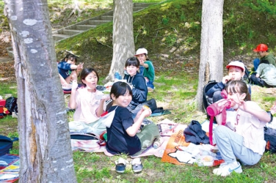 写真：遠足の昼食で楽しそうにお弁当を頬張る児童たち