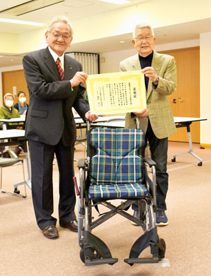 写真：室蘭社協の國枝会長（左）に車いすを寄贈した小林会長