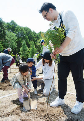 写真：苫小牧市で開かれた第７４回北海道植樹祭に参加し、丁寧に苗木を植える親子