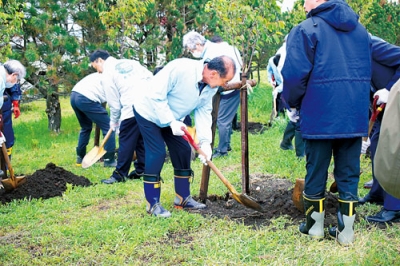写真：エゾヤマザクラの苗木を植樹する参加者ら