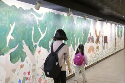 写真：通路壁面に描かれた壁画を見る親子＝２２日、札幌市