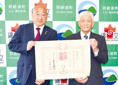 写真：勲記を手に記念写真に収まる篠原さん（右）と下道町長