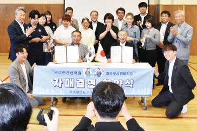 写真：協定書を手に記念撮影する菅野理事長（右）とキム代表