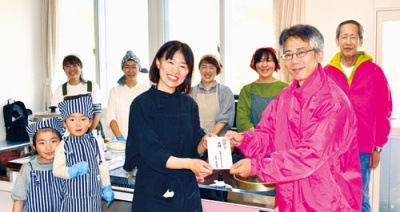 写真：「つながる△トーヤコビト食堂」に寄付する髙臣会長（右前）
