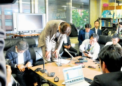 写真：２５日の会見で頭を下げる堀井氏。後継候補の選定などが今後本格化する