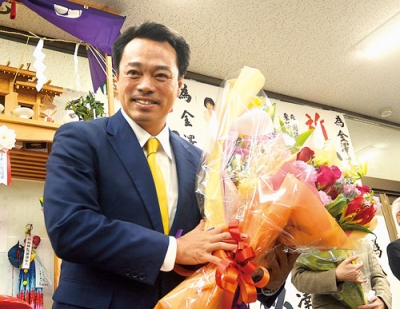 写真：初当選が決まり、花束を受け取り笑顔を見せる金澤氏＝８日午後１０時５６分、苫小牧市若草町の選挙事務所