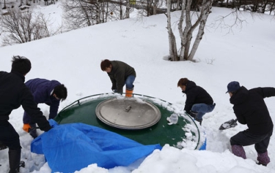 写真：雪の中から貯蔵タンクを掘り出す蔵人＝２１日午前、美瑛町