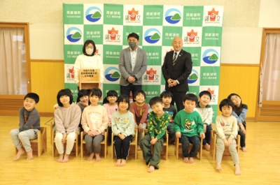 写真：木の椅子に座って笑顔を見せる子どもたち