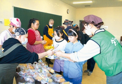 写真：袋詰めされたシフォンケーキとラスクを受け取る子どもたち